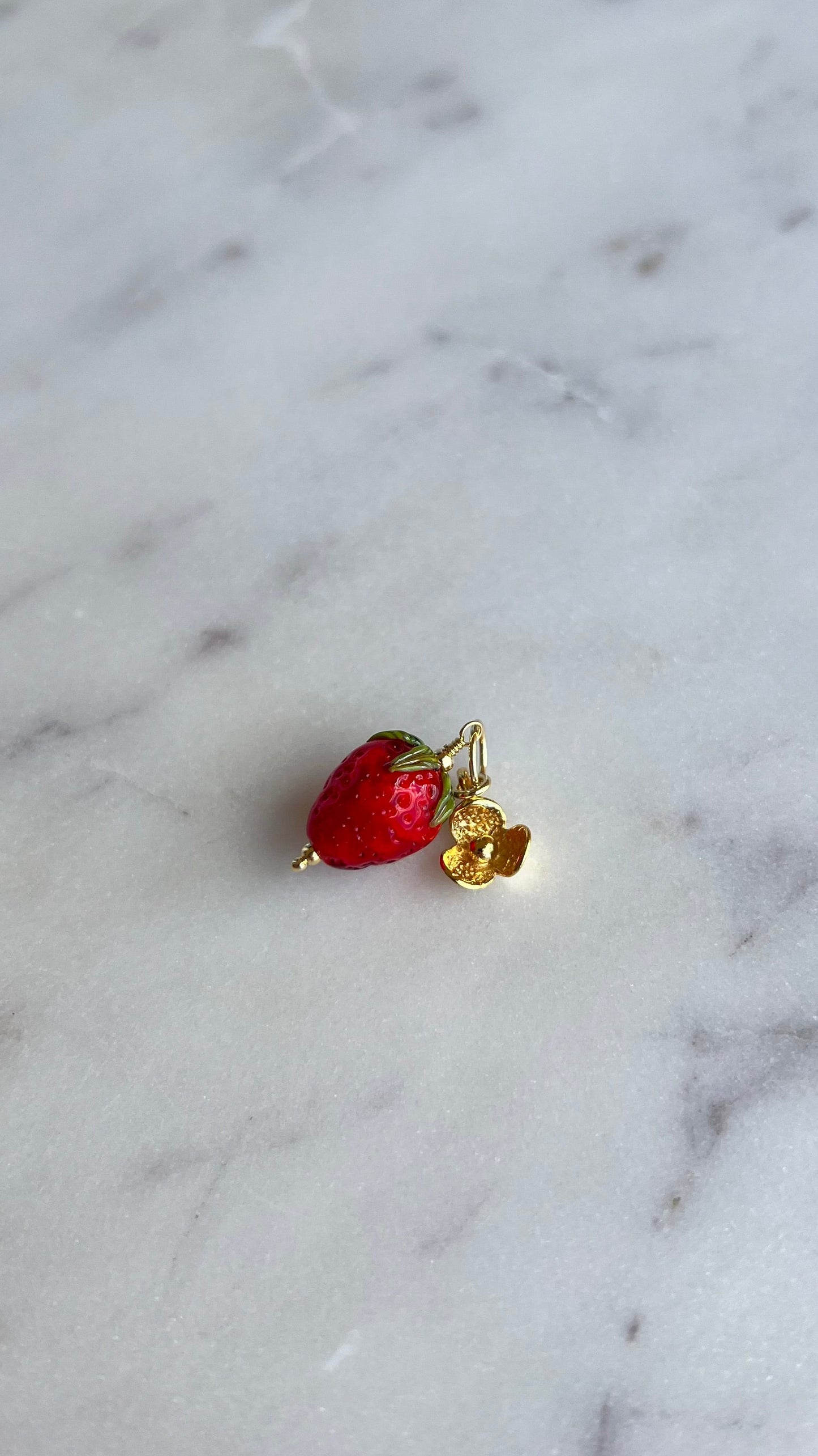 Zawieszka truskawka ze złotym kwiatem lotosu.