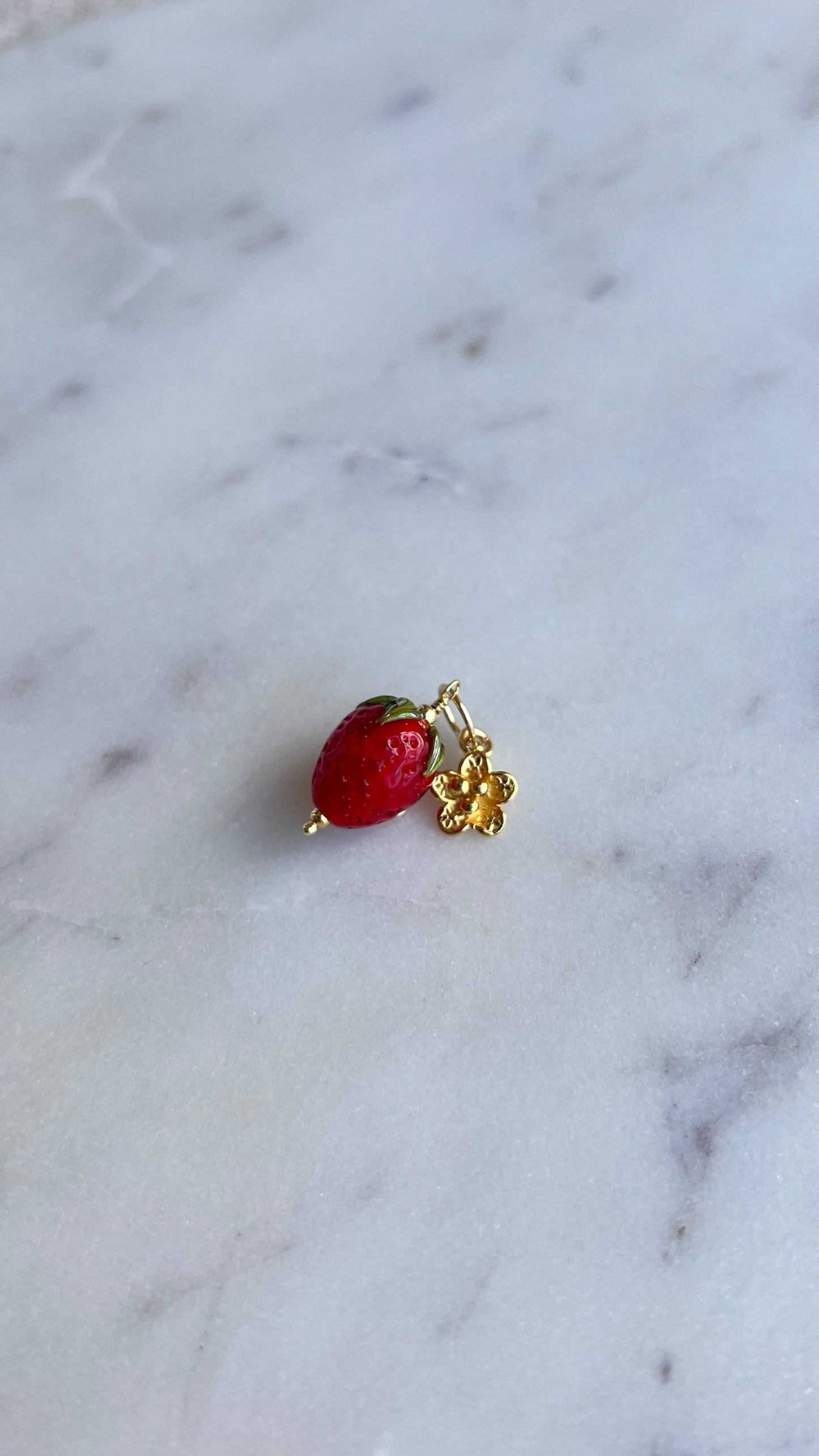 Zawieszka truskawka ze złotym rozkwitającym kwiatem.