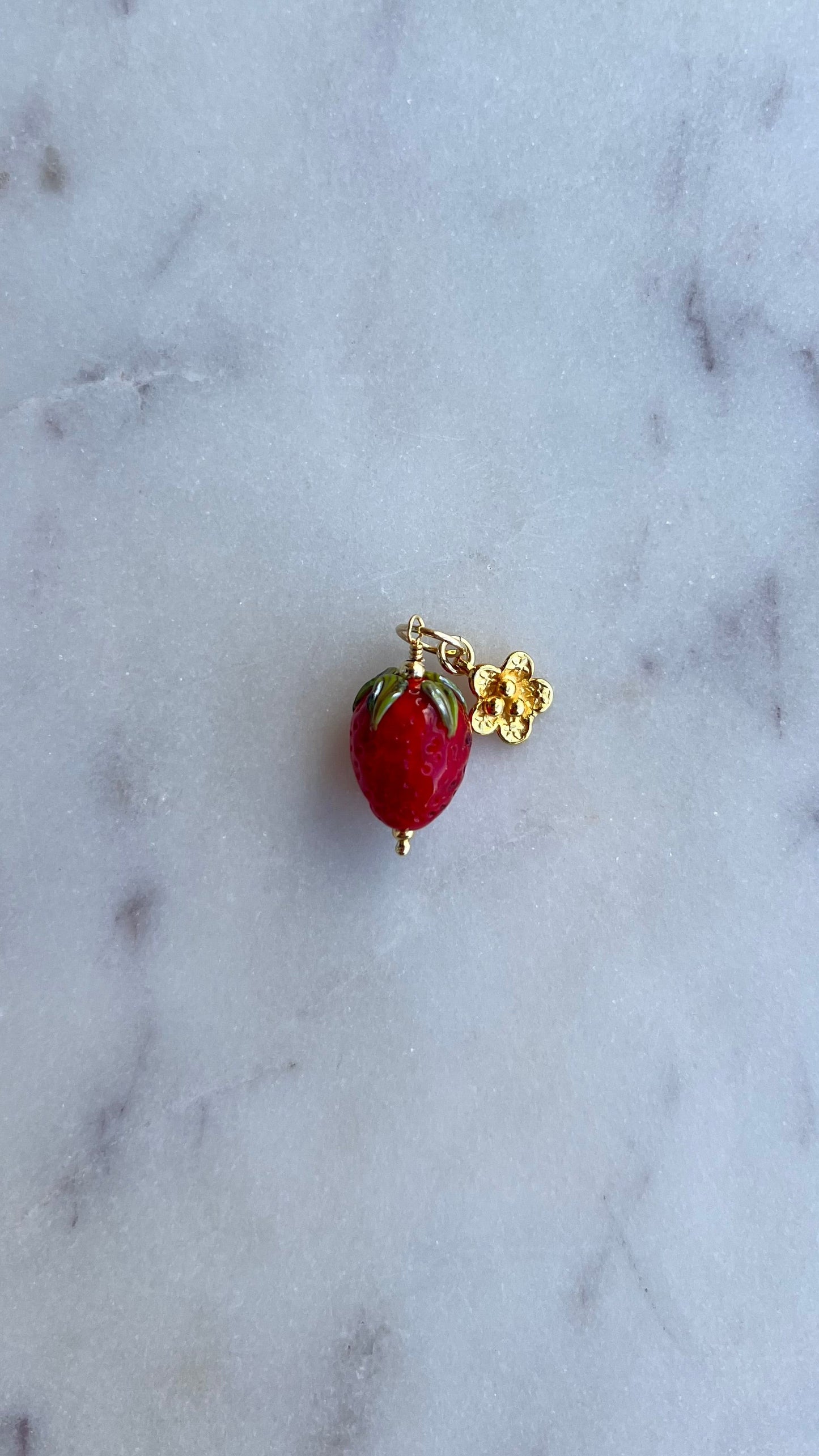 Zawieszka truskawka ze złotym rozkwitającym kwiatem.